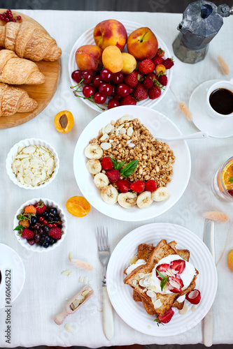 Fresh and bright continental breakfast table, abundance healthy meal variety crunch cereal, french toast, fruits, lemonade, coffee, croissant on  table served, top view, flat lay, copy space, frame..