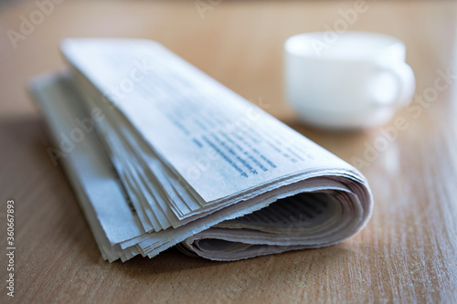 Folded newspaper on a wooden table with coffee