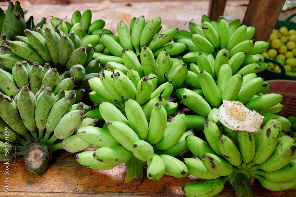 Fresh Green banana raws on wooden table in the market at Thailand