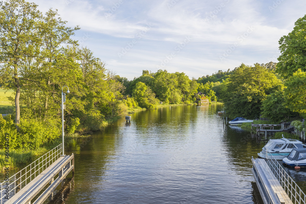 Beautiful landscape view of river with green forest trees on both sides and boats on blue sky background. Beautiful landscape view of river with green forest trees on both sides and boats on blue sky background.