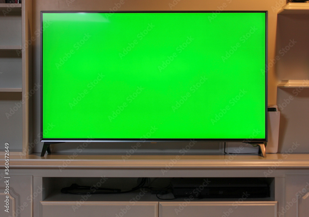 Close up of big green screen led TV in a cozy living room. Modern 55 inch  sized television with chroma key green screen over a TV unit. Stock-foto |  Adobe Stock