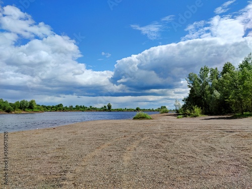 Fototapeta Naklejka Na Ścianę i Meble -  huge clouds in the blue sky above the river and the sandy shore