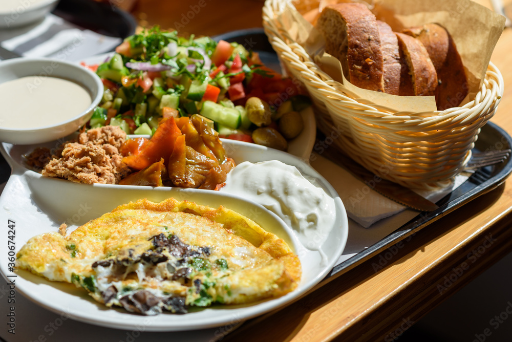 Israeli breakfast plate found in every cafe in Israel, this plate has everything that is good eggs per the diners request, different cheeses and condiments, fresh Israeli salad and a bread basket.