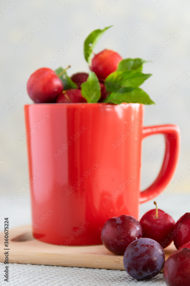 Fresh raw plums in red cup, healthy sweet food Fresh raw plums in red cup, healthy sweet food