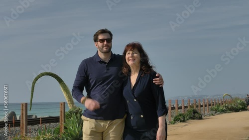 Happy Couple Enjoying Beautiful Day Walking holding hands on the Beach. CLose to Pacific surfliner rails Travel Vacation Retirement Lifestyle Concept California Orange county San clemente photo