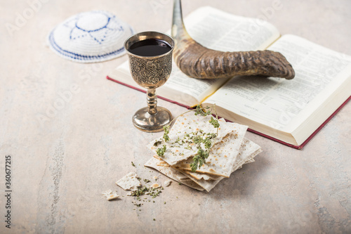 Passover, the Feast of Unleavened Bread, matzah and Kosher red wine glasses shofar (horn) with religious holy prayer book on table