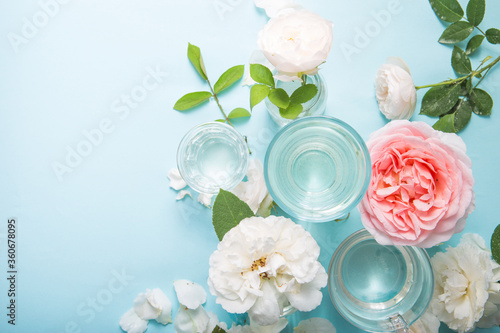 Spring fresh white, pink roses distorted through liquid water of glass on blue.