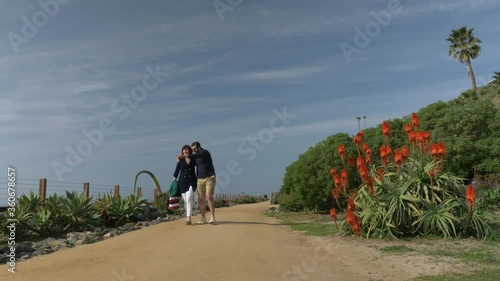 Happy Couple Enjoying Beautiful Day Walking holding hands on the Beach. CLose to Pacific surfliner rails Travel Vacation Retirement Lifestyle Concept California Orange county San clemente photo