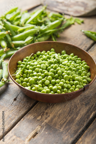 Young fresh green peas on wooden  table viewed from above
