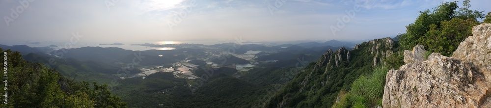 panoramic view from a top of a mountain where we can see the sea with islands, farms and rocks and trees