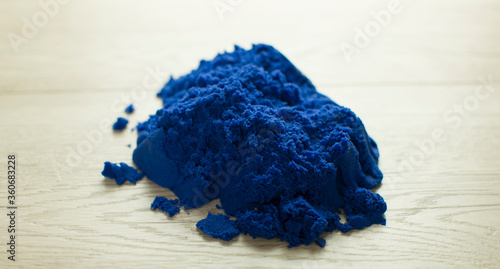 Kinetic natural colored sand on a light wood background.