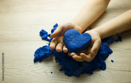 Heart of sand in the hands of a child. Sand therapy.