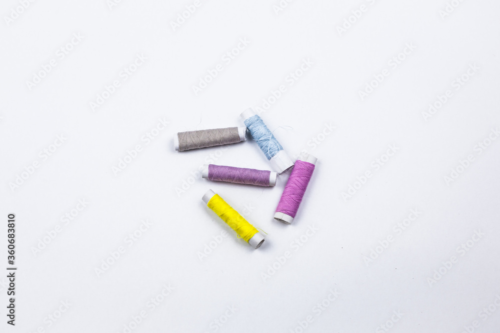 Naklejka premium Coloured sewing threads on white background.