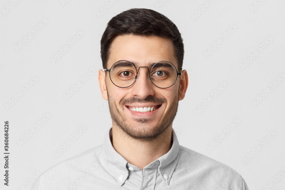 Smart businessman smiling at camera, wearing round glasses, isolated on gray background Smart businessman smiling at camera, wearing round glasses, isolated on gray background