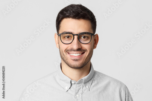 Eyewear fashion. Headshot portrait of handsome smiling man dressed in gray shirt and wearing eyeglasses, isolated on studio background