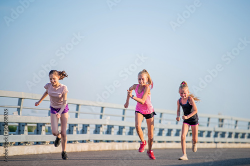 Girls compete on the asphalt road against the evening sky