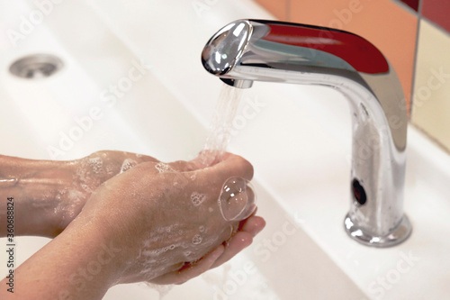 A person washes their hands in a public place. Prevention of infection with viruses and bacteria.