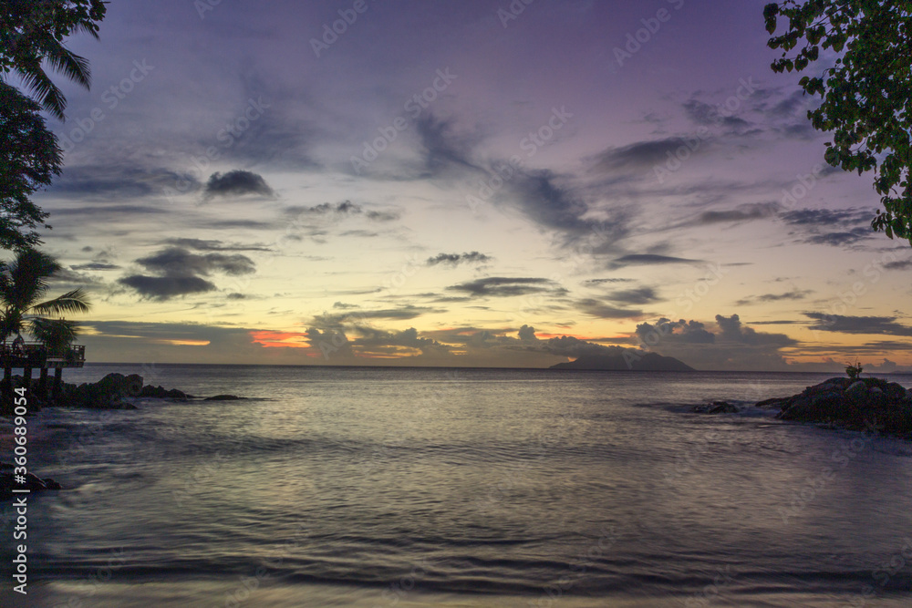 Landscape beautiful colorful golden sunset red, orange and purple sky Seychelles. Serenity and calm concept. The sun sets behind the horizon on a cloudy day.