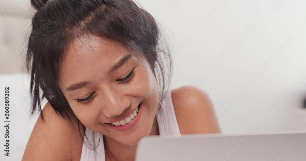 Portrait of young asian woman using laptop with smile on bed. Portrait of young asian woman using laptop with smile on bed.