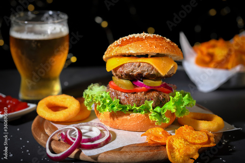 Big hamburger with salad, french fries, onion rings and cheese.