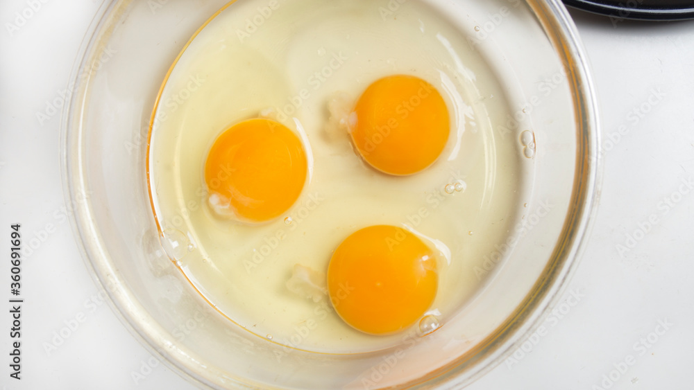 three broken eggs for making French omelet in a glass bowl before whipping three broken eggs for making French omelet in a glass bowl before whipping
