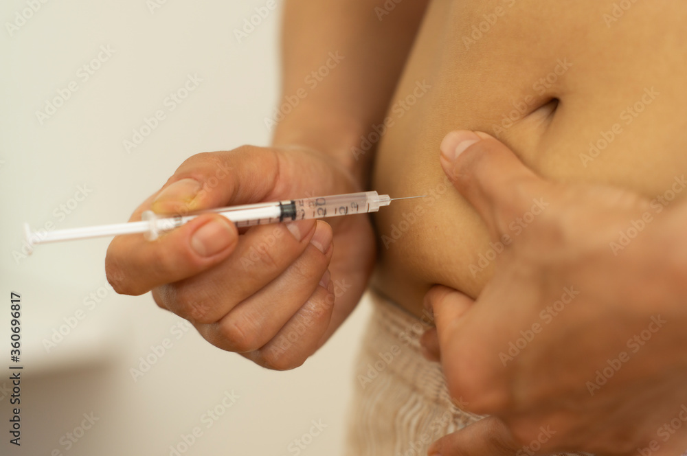 Woman with syringe inject insulin to her belly - diabetes concept, injection Woman with syringe inject insulin to her belly - diabetes concept, injection