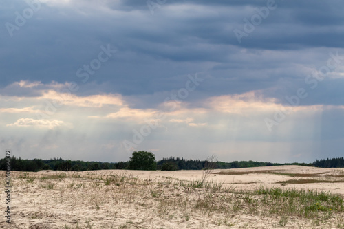Desert in spring distant view on sand dunes near forest with epic dark sky. Kitsevka desert hilly sands in Ukraine  Kharkiv region landscape