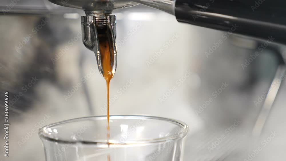 Making fresh coffee beverage going out from coffee espresso machine. Slow motion food video. Espresso coffee being brewed by automatic machine flowing into cup at bar or cafe. Full hd