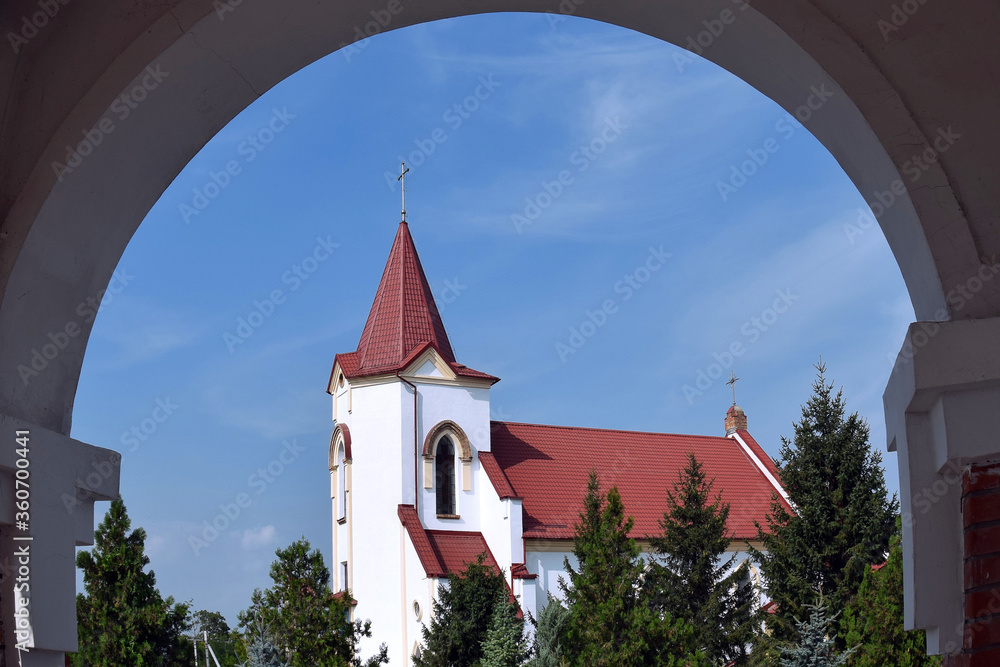 View through arch on Roman Catholic Church of St. Joseph.  Church is built in  Gothic style. Walls of building are painted white.