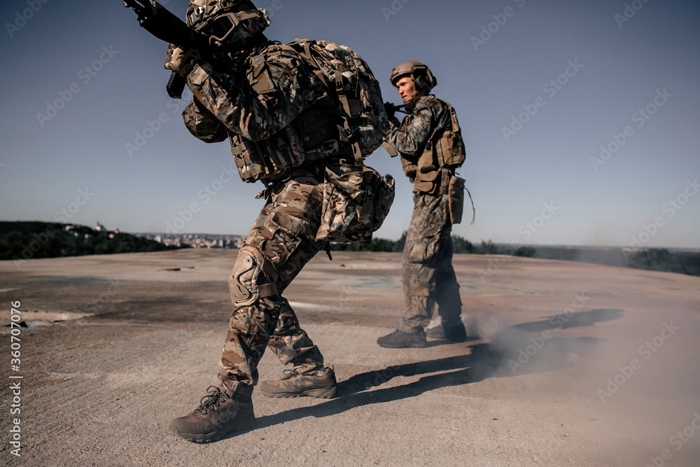 Φωτογραφία Two us army soldiers in camouflage standing on the roof of a building with a rif
