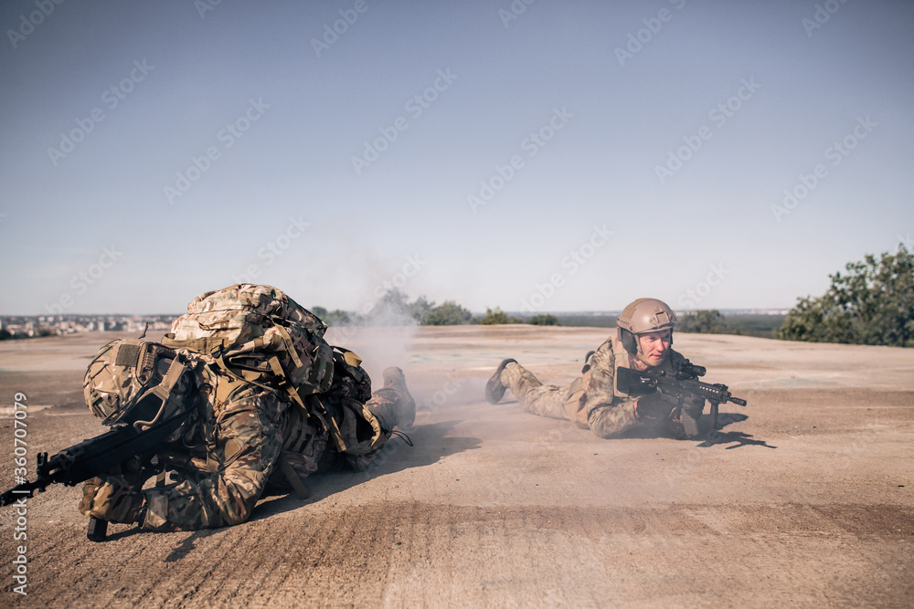 Φωτογραφία Two us army soldiers in camouflage lie on the roof of a building with a rifle ai