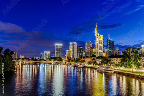 Frankfurt am Main. European finance center city downtown skyline cityscape. Eiserner steg bridge, river during twilight blue hour, sunset, evening, night. Gold yellow color. Travel in Hesse, Germany. © Mikalai