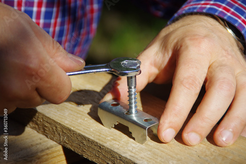 A carpenter with a wrench in hand tightens the screw