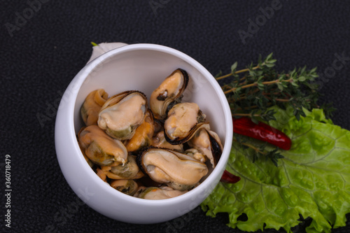 Pickled mussels in the bowl served pepper, garlic and salad