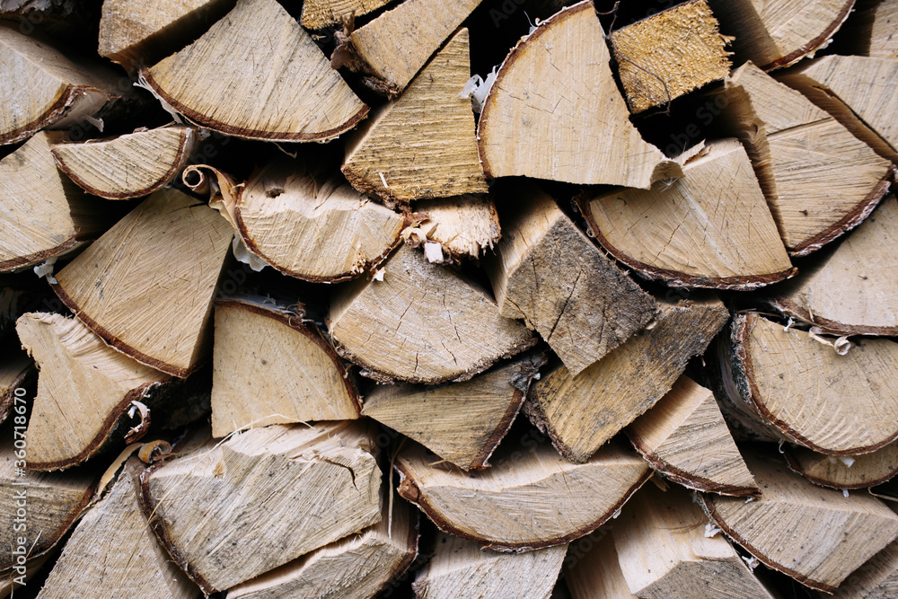 Fototapeta premium Closeup photo of many firewood evenly stacked against the wall. Dry wood logs. Beautiful texture.