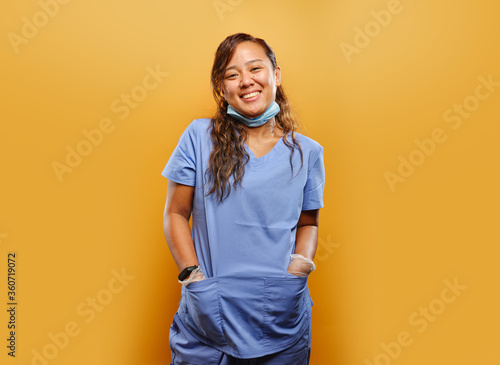 portrait of happy filipina nurse on orange background