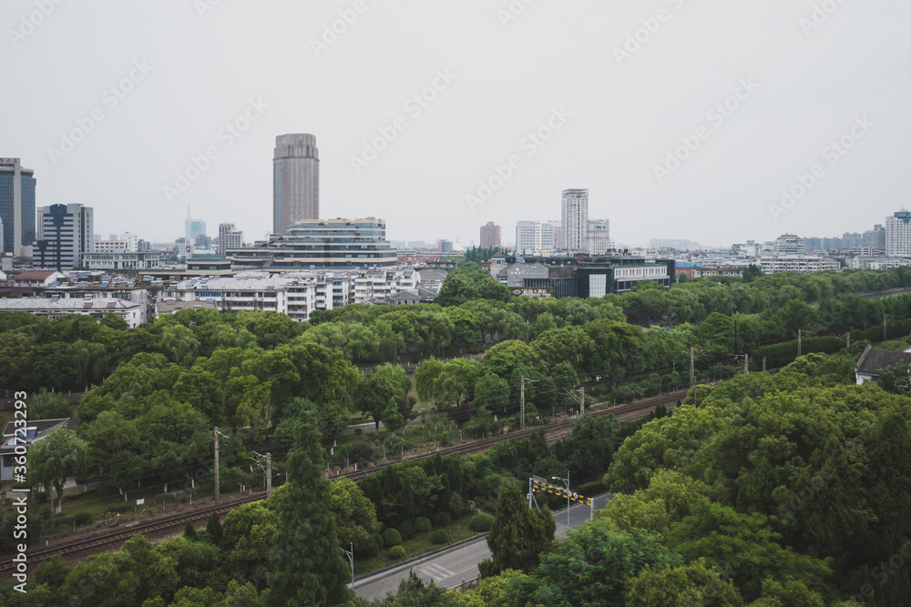 Railway between trees and city skyline viewed from South Lake scenic area in Jiaxing, China