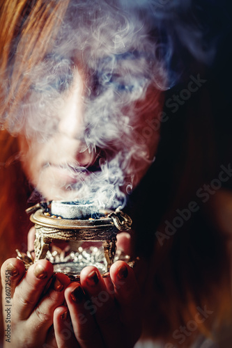 incense in a woman hand, incense smoke on a black background. photo