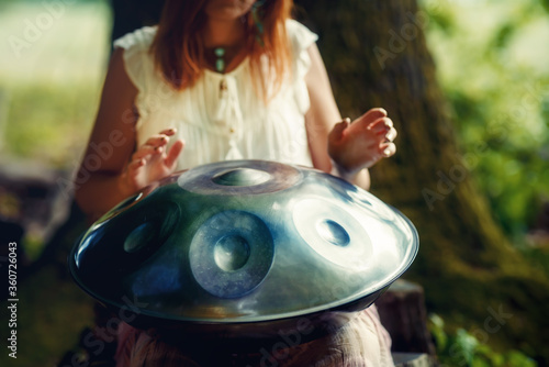 beautiful woman playing with hangdrum in nature.