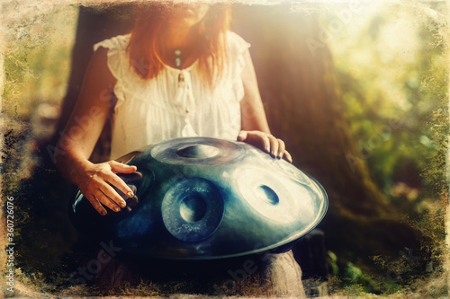 beautiful woman playing with hangdrum in nature. Old photo effect. photo