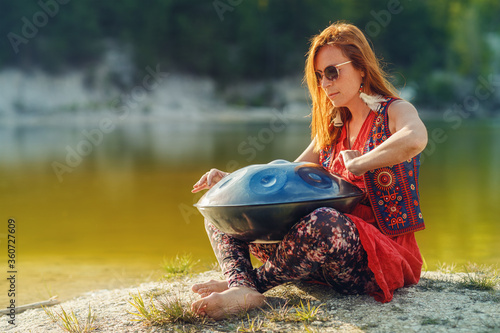 beautiful woman playing with hangdrum in nature. photo