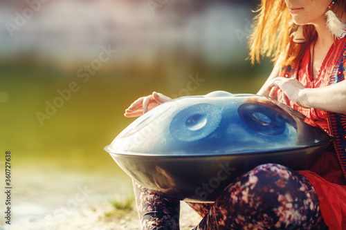 beautiful woman playing with hangdrum in nature. photo