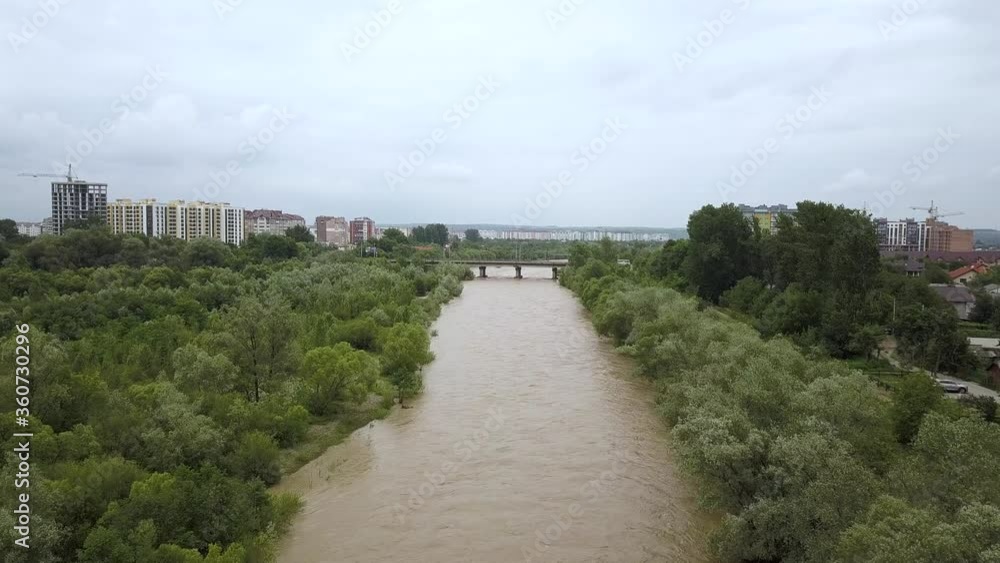 Aerial view of wide dirty river with muddy yellow water flowing through a city in flooding period during heavy rains in spring.
Aerial view of wide dirty river with muddy yellow water flowing through a city in flooding period during heavy rains in spring.