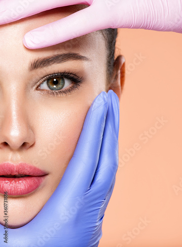 Face skin check before plastic surgery. Beautician touching young woman face. Doctor in medicine gloves checks a skin before plastic surgery. Beauty treatments.