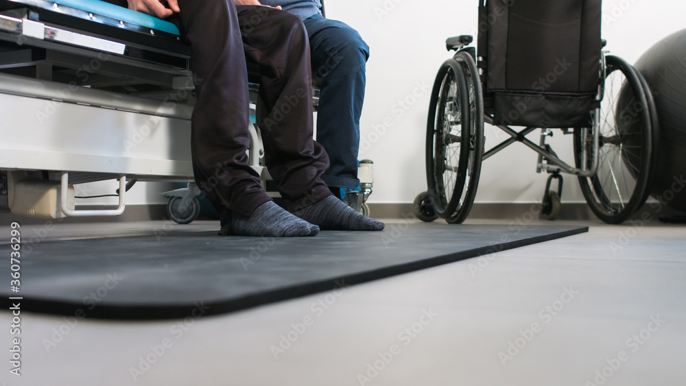 Physiotherapist exercising with disabled person using wheelchair on a therapy table. Physiotherapist exercising with disabled person using wheelchair on a therapy table.