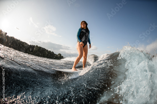 young woman wakesurfing down the river waves