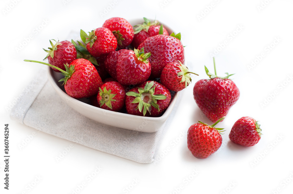 Breakfast with strawberries on white background. Breakfast for child. Strawberries in a white heart-shaped bowl Breakfast with strawberries on white background. Breakfast for child. Strawberries in a white heart-shaped bowl