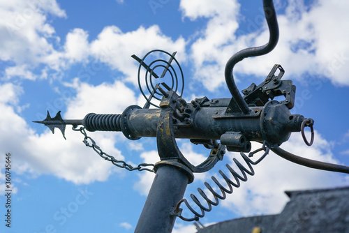 Harpoon whaling weapon on a background of blue sky with clouds. Vintage