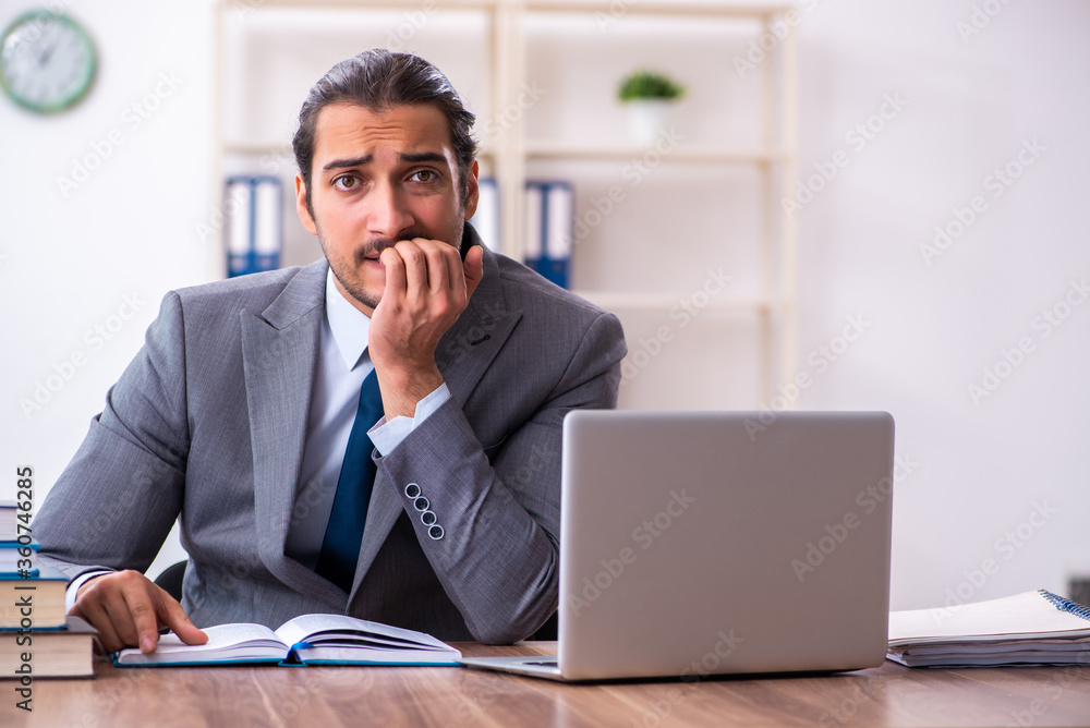 Young male businessman reading books at workplace Young male businessman reading books at workplace