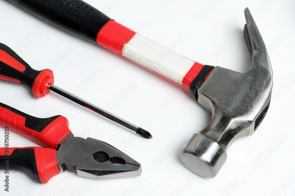 Screwdriver, hammer and pliers on a white wooden background Screwdriver, hammer and pliers on a white wooden background